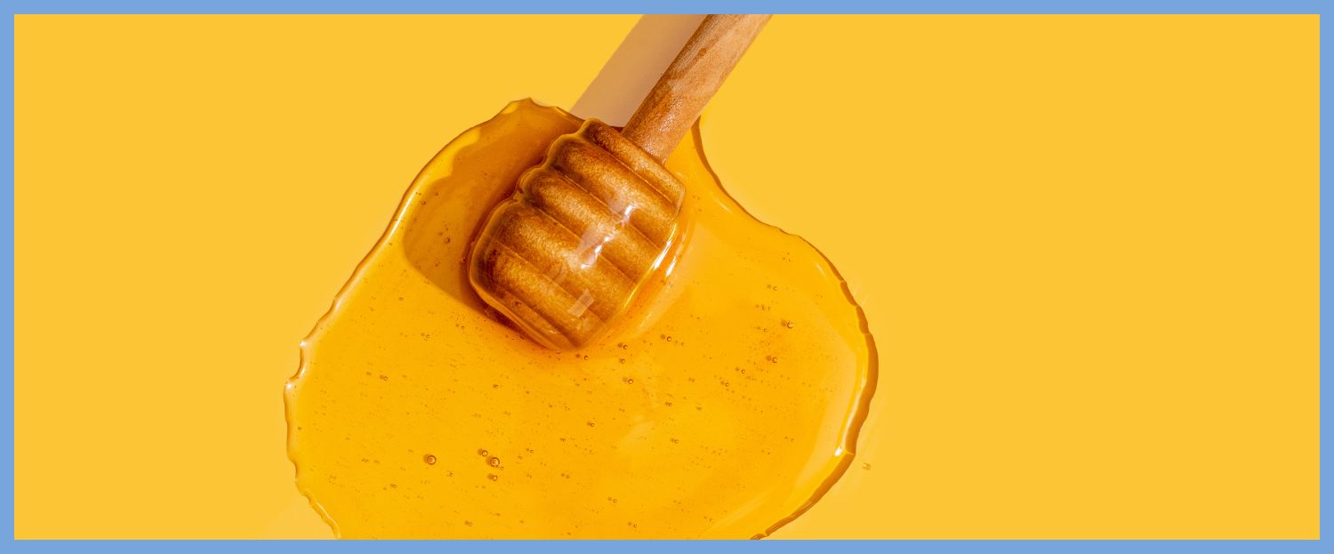 honey on a yellow background with a wooden dipper