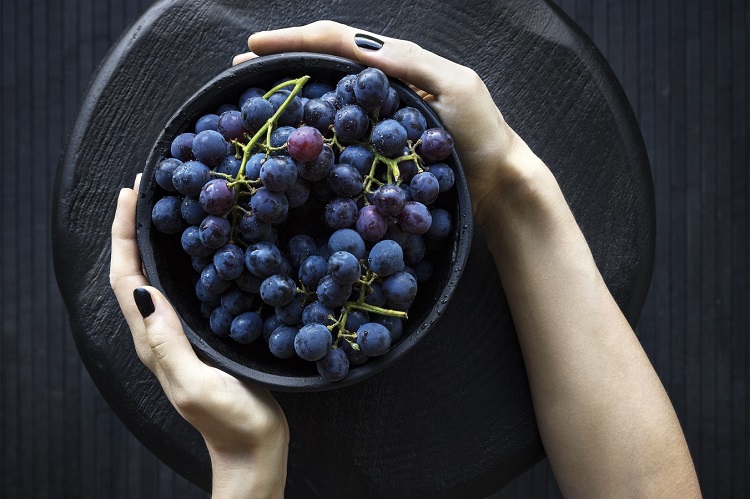 person holding a bowl of grapes